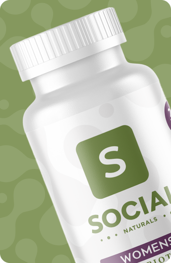 White Social Naturals Womens Probiotic supplement bottle with green and purple label on a green background.